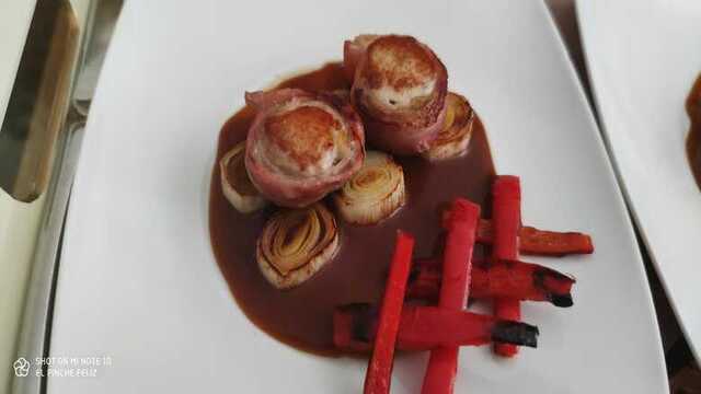 Lomito de conejo albardado con bacon sobre puerros y pimientos braseados